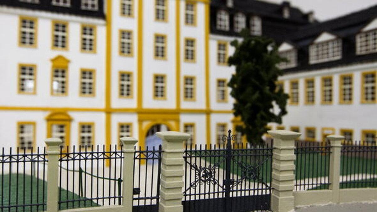 Modell 'Altes Regierungsgebäude' in der Burgstraße, im Vordergrund die Umzäunung des Gebäudes mit Wegen zum Eingang, die seitlich begrünt sind. Das Gebäude selbst ist in gelb und weiß gehalten.
