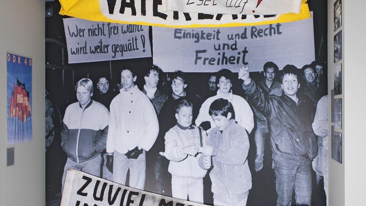 Blick in die Ausstellung - Großfoto der Demonstration in Gera am 23. November 1989, davor Transparente von Geraer Demonstrationen vom November/Dezember 1989