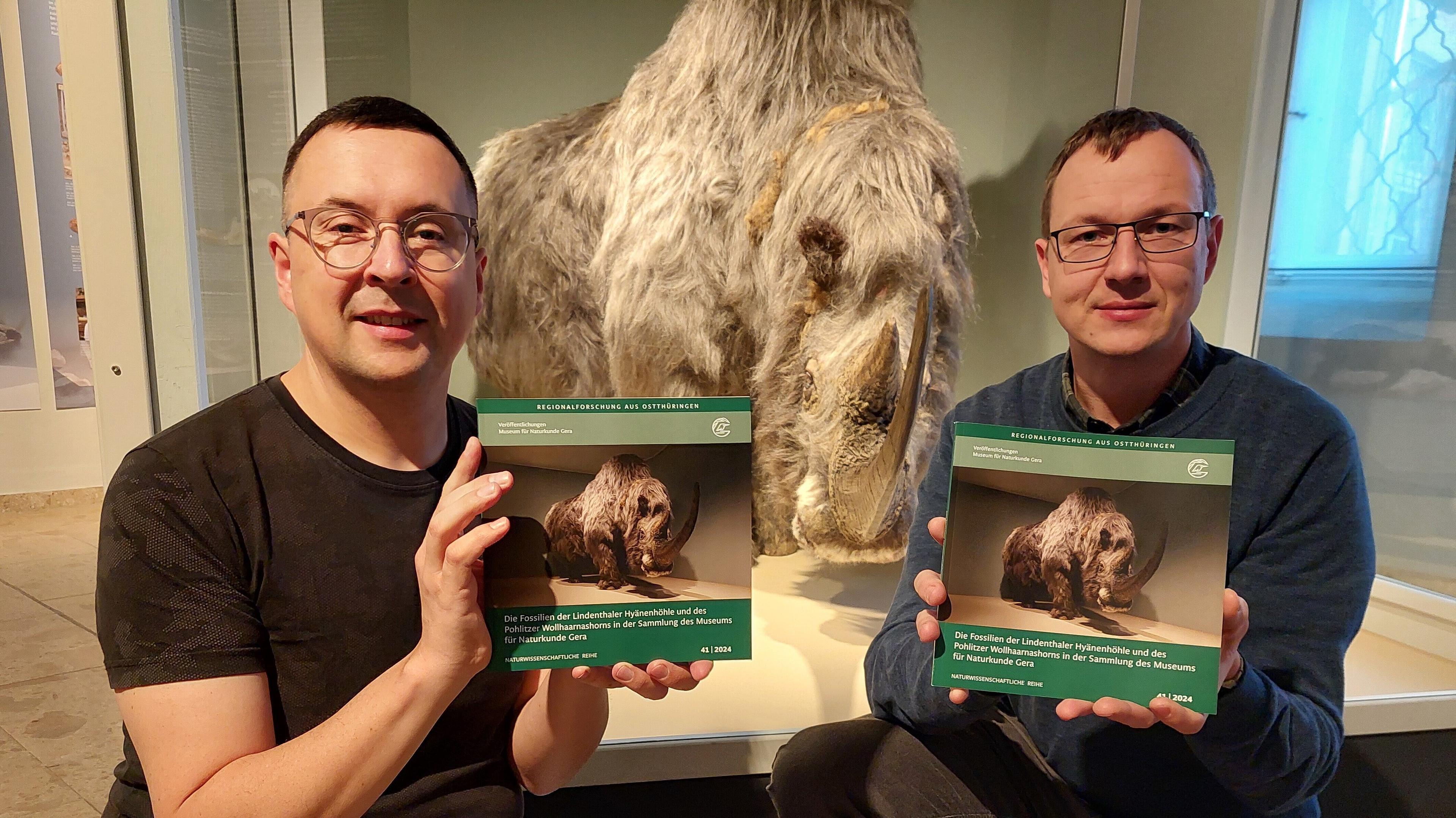 Frank Hrouda (links) und Dr. Andreas Gerth (rechts) präsentieren das neue Buch der Veröffentlichungsreihe des Museum für Naturkunde Gera über die Lindenthaler Hyänenhöhle und das Pohlitzer Wollhaarnashorn. © Stadt Gera / Museum für Naturkunde (Fotograf: Rainer Michelsson)