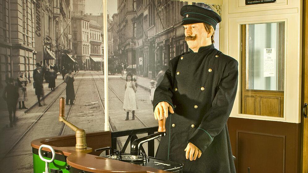 Ausstellungsinszenierung mit einer Straßenbahn um 1900 und Straßenbahnfahrer. Im Hintergrund ist die Schlossstraße mit Straßenbahnschienen zu sehen und eine Werbetafel mit verschiedenen Anzeigen. © Ulrich Fischer