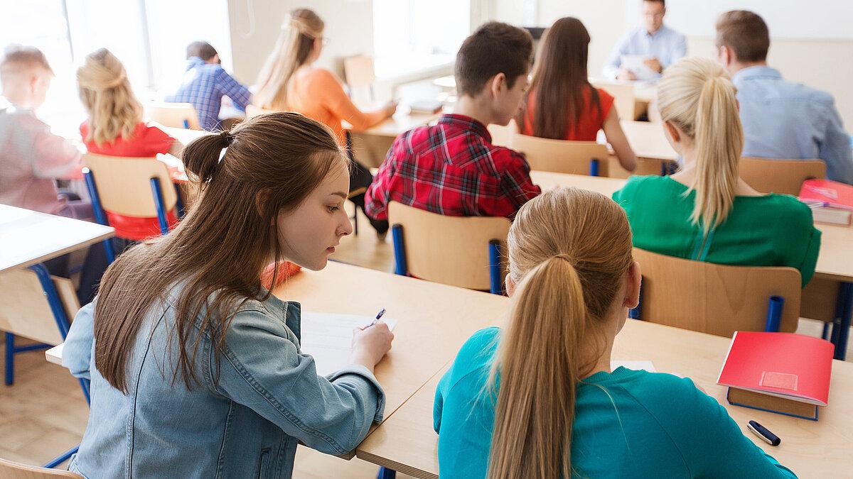 Symbolbild Schule, Schüler sitzen an ihre Tischen. © stock.adobe.com
