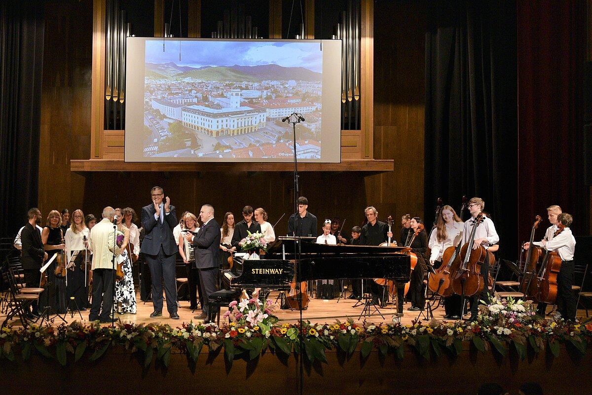 große Bühne mit vielen Musikerinnen und Musikern, die ihre Orchesteinstrumente in den Händen halten. © Stadt Gera