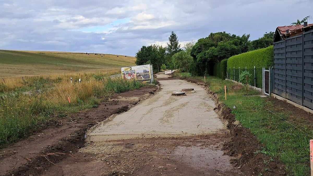 Eine sich im Bau befindluiche Straße, links ein Feld, rechts Wohnhäuser. © Stadt Gera