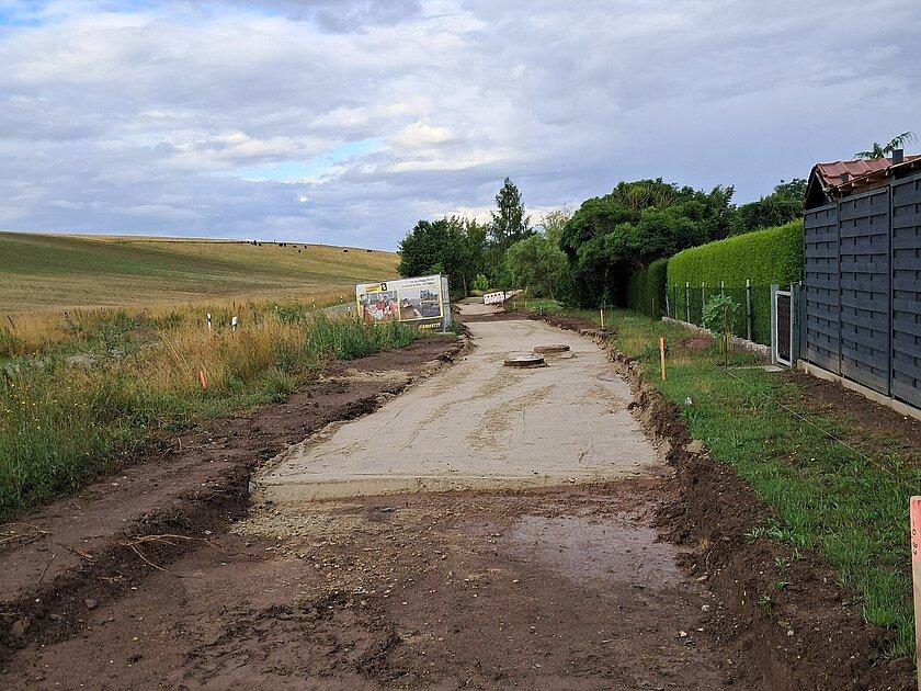 Eine sich im Bau befindluiche Straße, links ein Feld, rechts Wohnhäuser. © Stadt Gera
