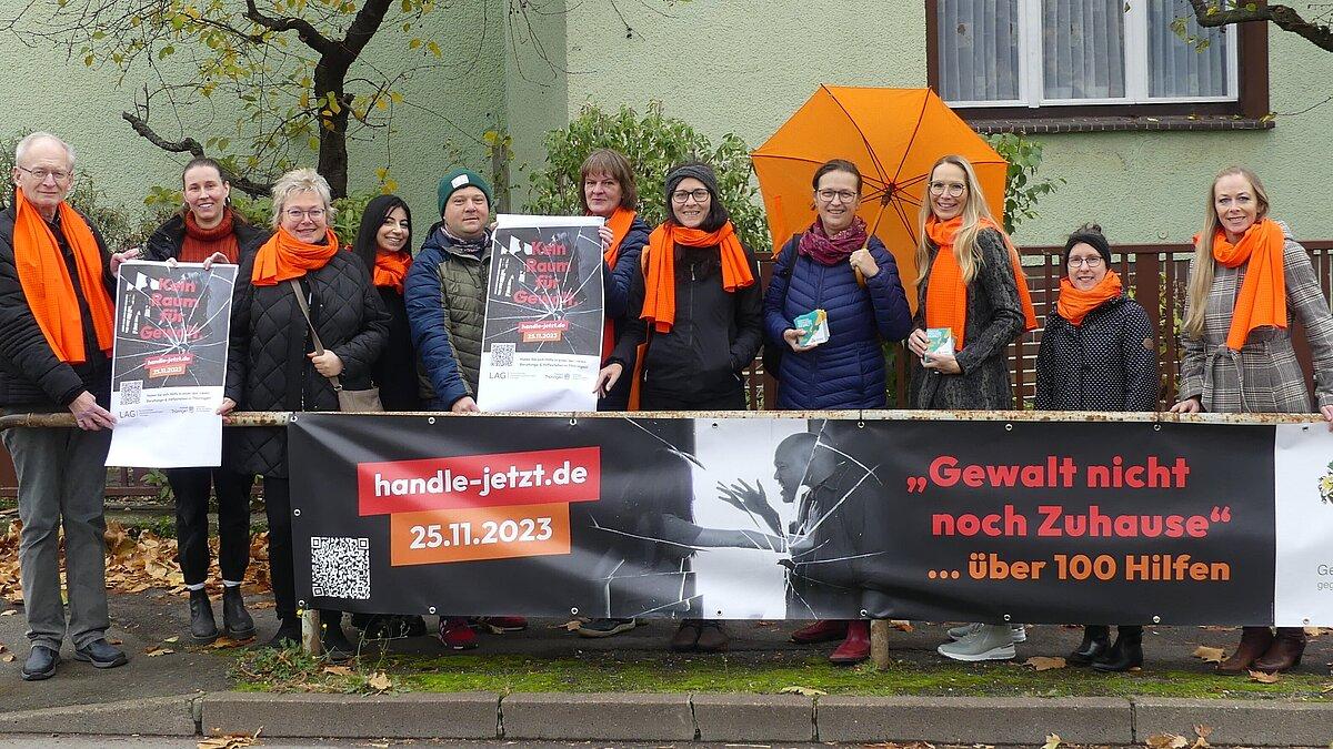 An vier Kreuzungsgeländern in Gera vermitteln Planen mit QR-Code auf www.handle-jetzt.de. Darauf machten zum „Kreuzungsplanentreff“ aufmerksam (v.l.): Hubert Grieser, Weißer Ring Außenstellenleiter Gera; Katharina Naujoks, Projekt Orange; Catrin Heinrich, Gleichstellungsbeauftragte Gera; Anika Böttger, Praktikantin Frauenhaus Gera; Robert Werkmeister, Frauenkommunikationszentrum SOS Kinderdorf Thüringen; Uta Kühnhold, Frauenhaus Gera; Mirjam Quenzler, Frauenhaus Gera; Kathrin Engel, Interventionsstelle GeSa; Sandra Wanzar, Dezernentin für Jugend und Soziales; Anke Lubrich, Trägerwerk Soziale Dienste in Thüringen gGmbH; Fanny Rusche, Jobcenter Gera.