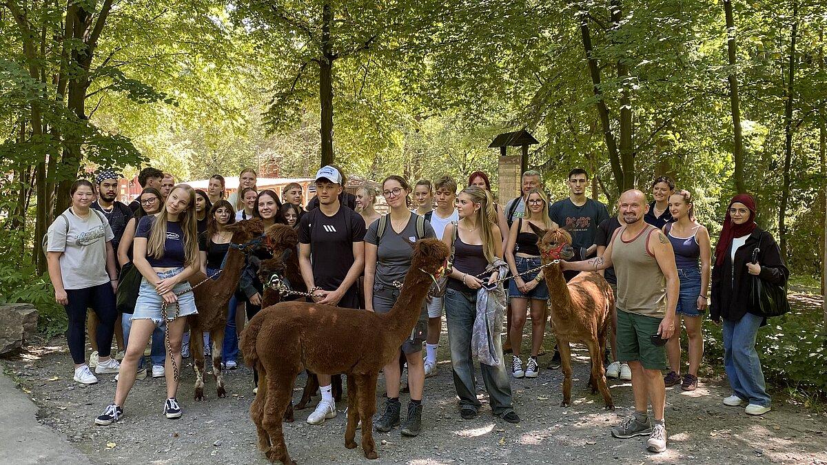 eine große Gruppe von Schülerinnen und Schülern stehen zum Gruppenfoto mit Alpakas im Tierpark. © Stadtverwaltung Gera