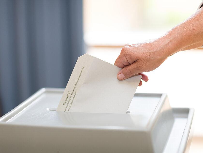 eine Person gibt ihren Stimmzettel ab. © Christian Schwier_stock.adobe.com