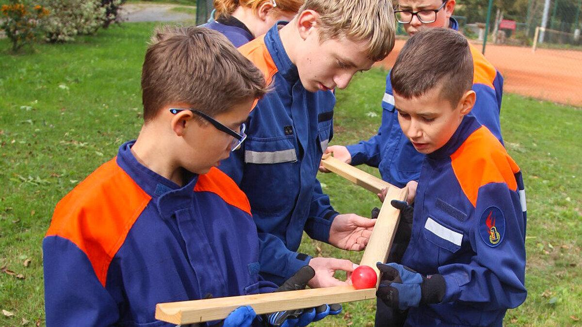 Jugendfeuerwehr muss einen Ball durch Teamwork balancieren