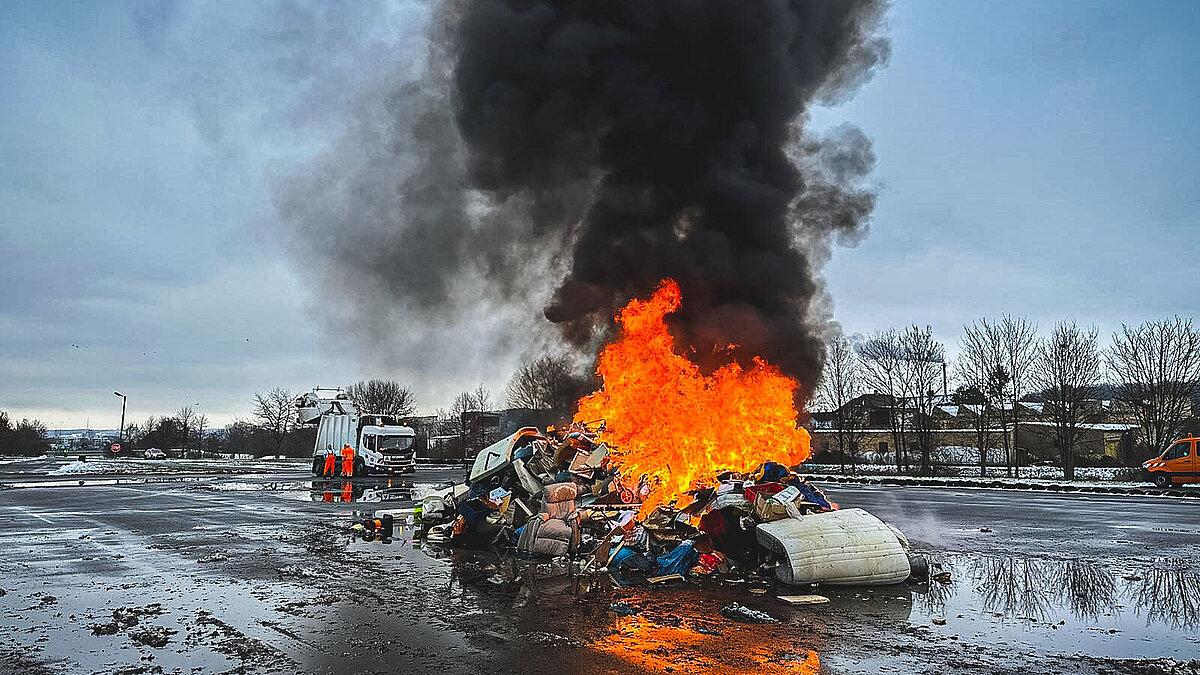 Angezündeter Schrotthaufen wird gelöscht. © Amt für Brand- und Katastrophenschutz