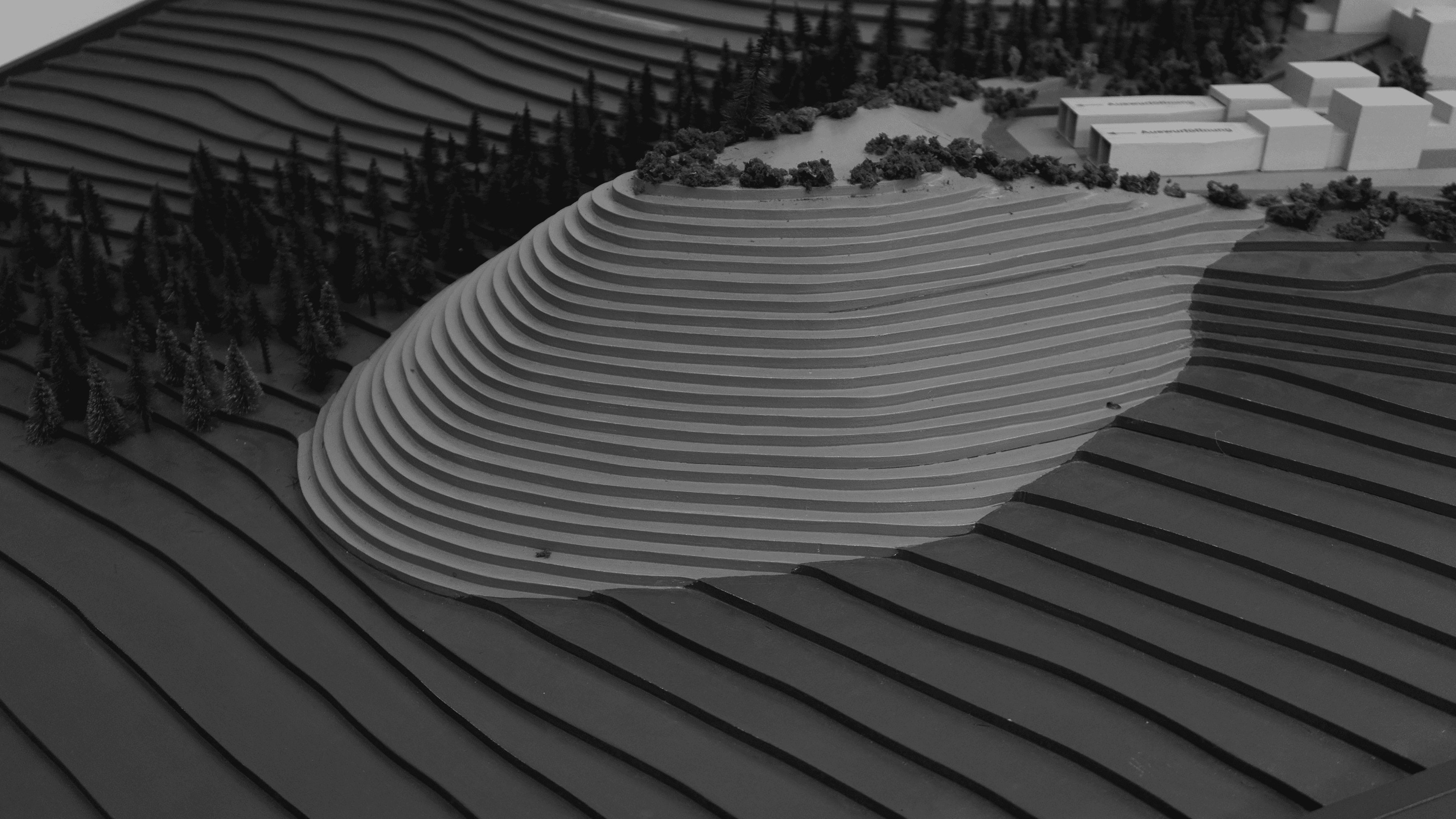 Schwarzweißfotografie von einem Modell einer Bergbaufolgelandschaft. Die terrassenartige Struktur des Modells erzeugt ein Spiel von Licht und Schatten.. © Felicitas Fäßler