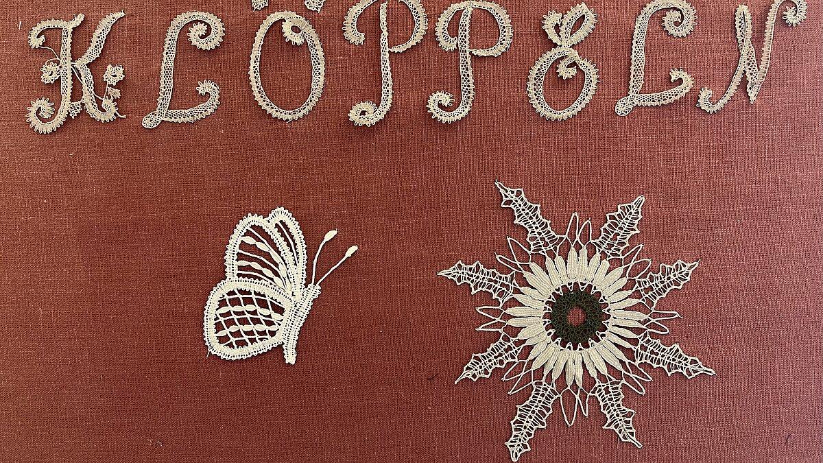 kleiner Klöppelschmuck aus Buchstaben, Blumen und Schmetterlingen