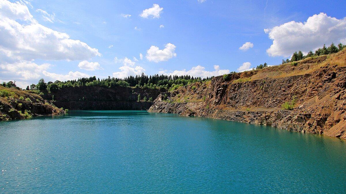 Blick in den Steinbruch Kahlleite 2017 mit großer blauer Wasserfläche in Vordergrund
