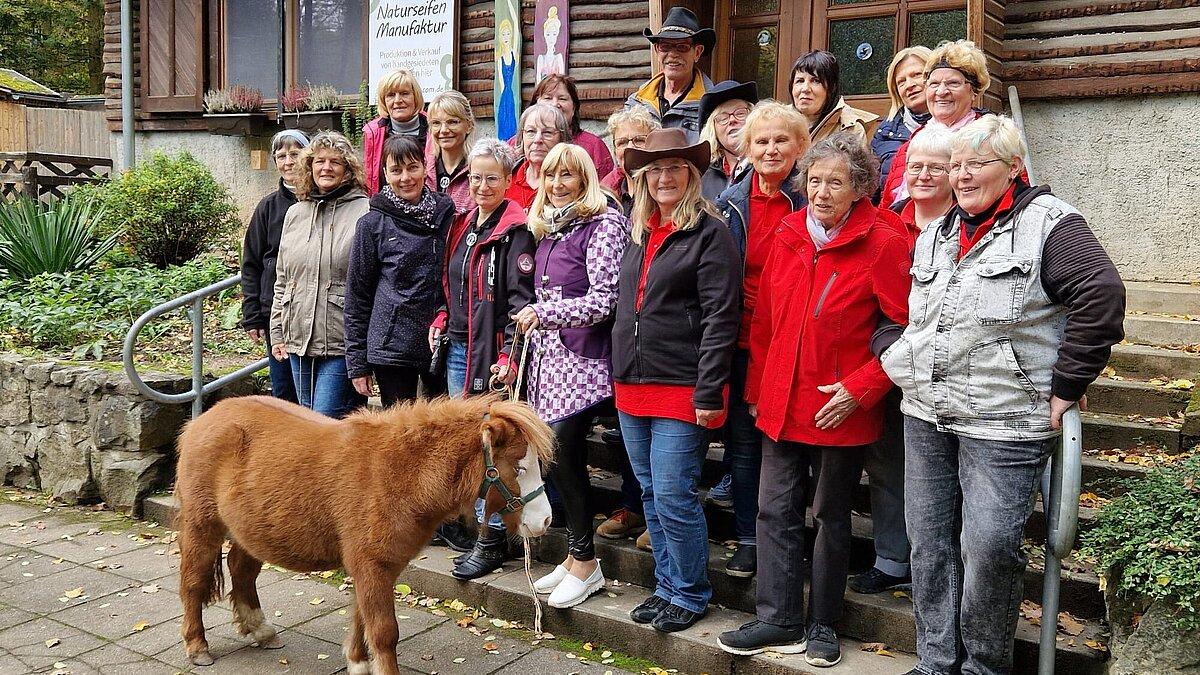 eine Gruppe von Menschen und ein Pony im Vordergrund.