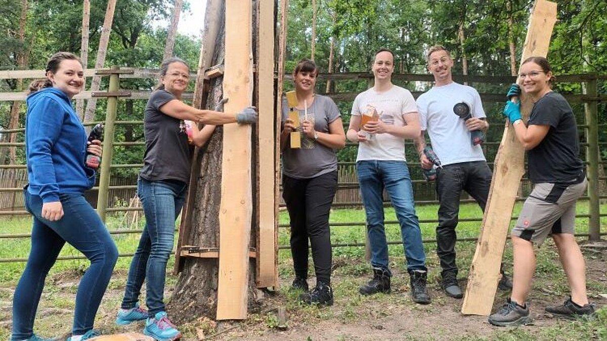 eine Gruppe von Leuten stehen mit Handwerkssachen im Gehege und bringen einen Bretter als Schutz an einen Baum an. © Stadtverwaltung Gera