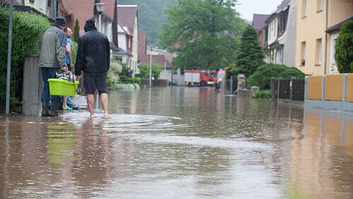 3 Personen auf der überfluteten Straße im Hochwasser. © Amt für Brand- und Katastrophenschutz