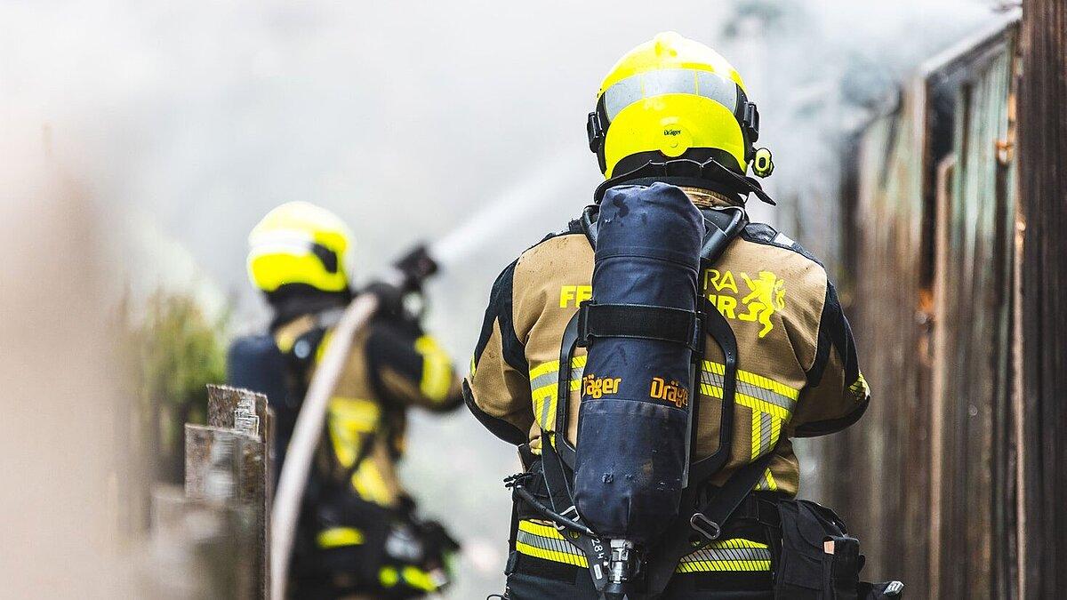 Zwei Feuerwehrmänner löschen einen Brand