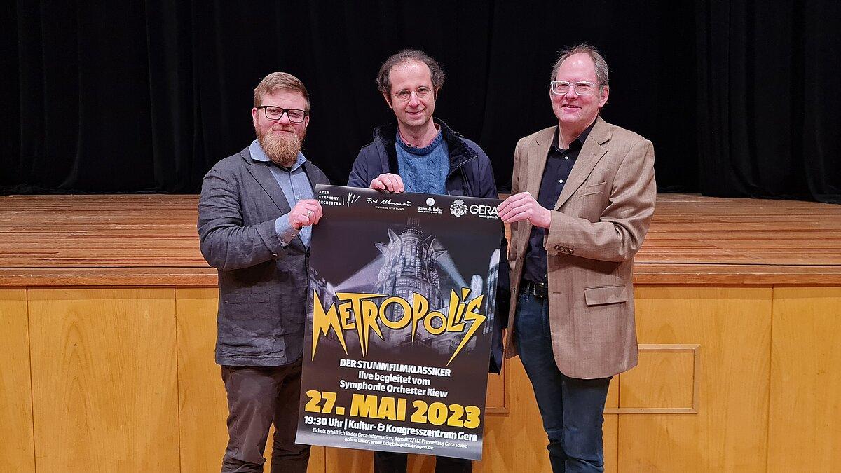 3 Herren, die ein Plakat von "Metropolis" halten. © Stadt Gera
