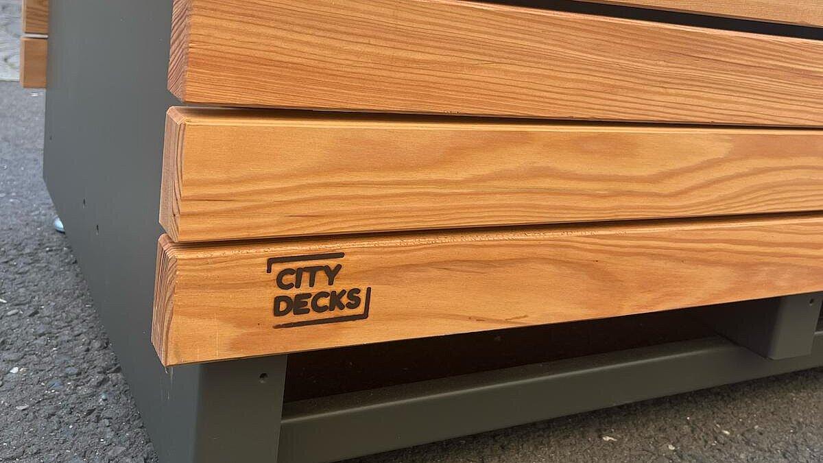 Eine neue Bank mit hölzerner Sitzfläche in der Fußgängerzone. © Stadt Gera