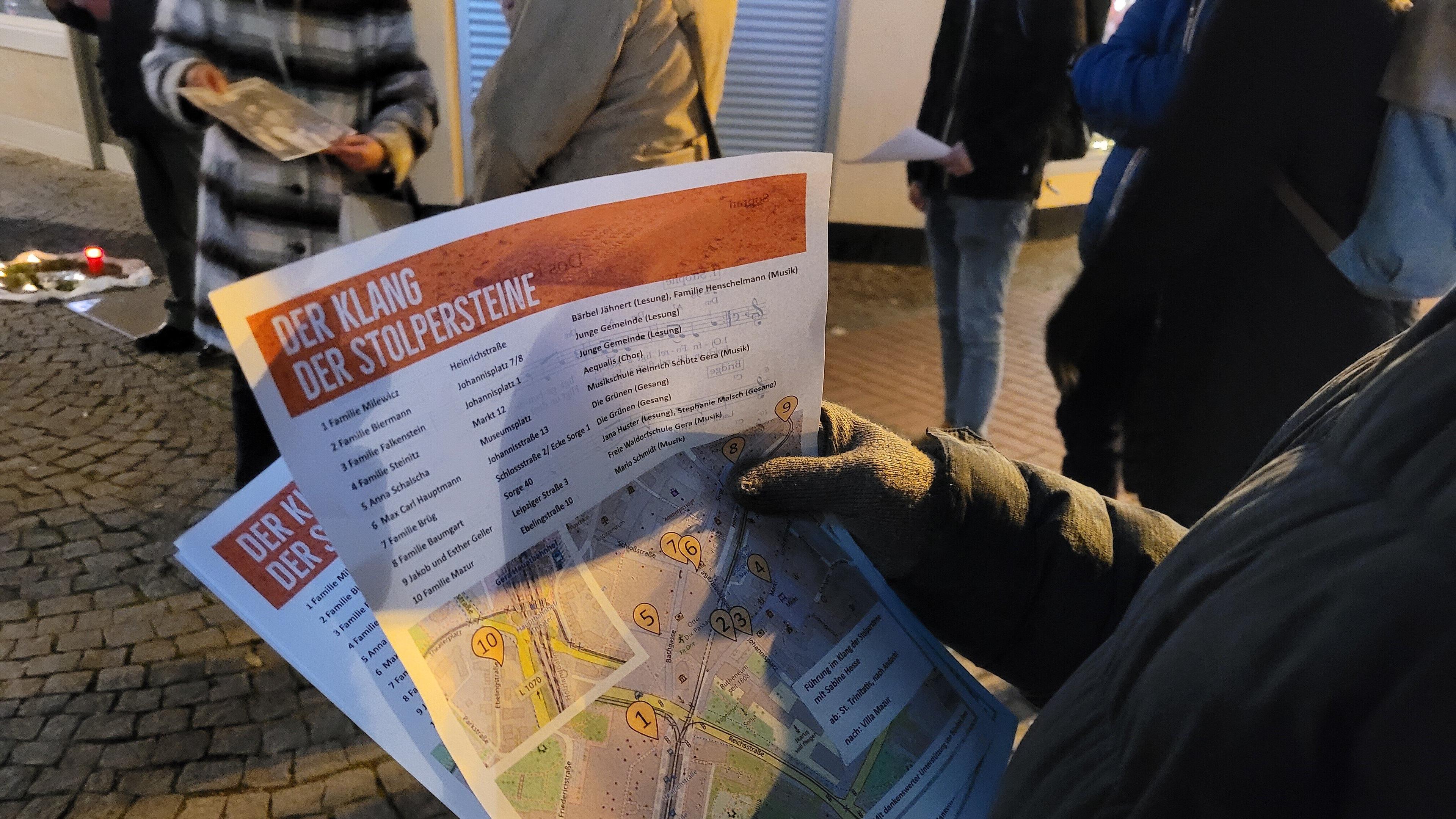 Auschnitt von einem Menschen, ab Gesicht abwärts, der ein Informationsblatt in der Hand hält. © Arbeitskreis Klang der Stolpersteine