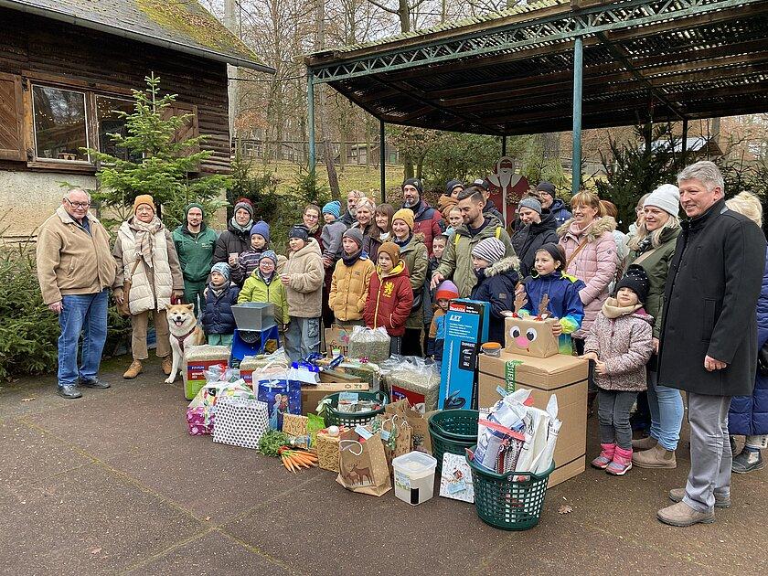 Geschenke und Überbringer stehen vor der weihnachtlich geschmückten Bühne im Tierpark Gera zur Bescherung. © Stadtverwaltung Gera
