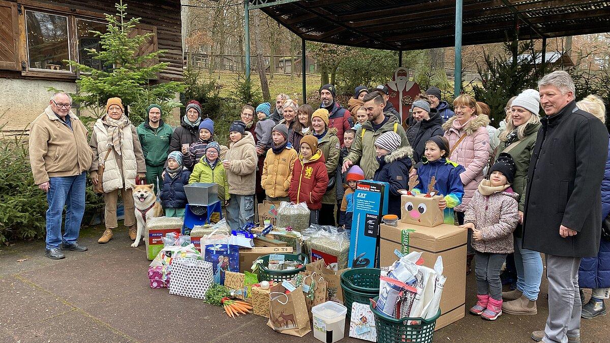 Geschenke und Überbringer stehen vor der weihnachtlich geschmückten Bühne im Tierpark Gera zur Bescherung. © Stadtverwaltung Gera