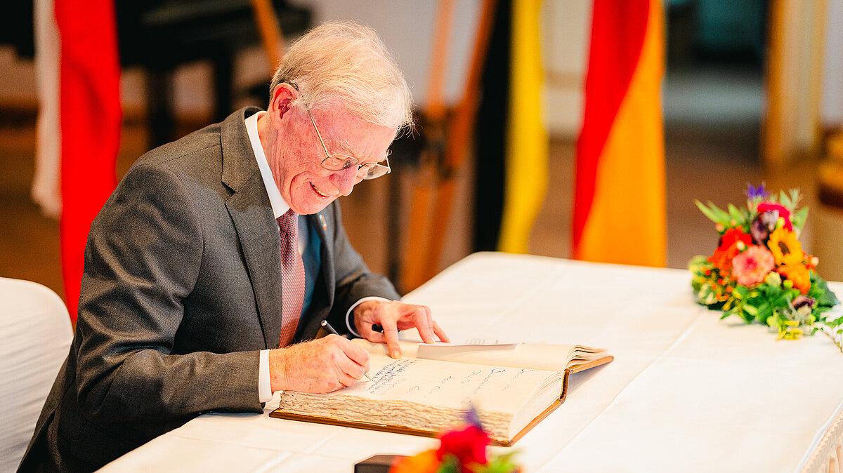 Horst Köhler sitzt an einem Tisch und schreibt in ein Buch.. © Tony Matysik