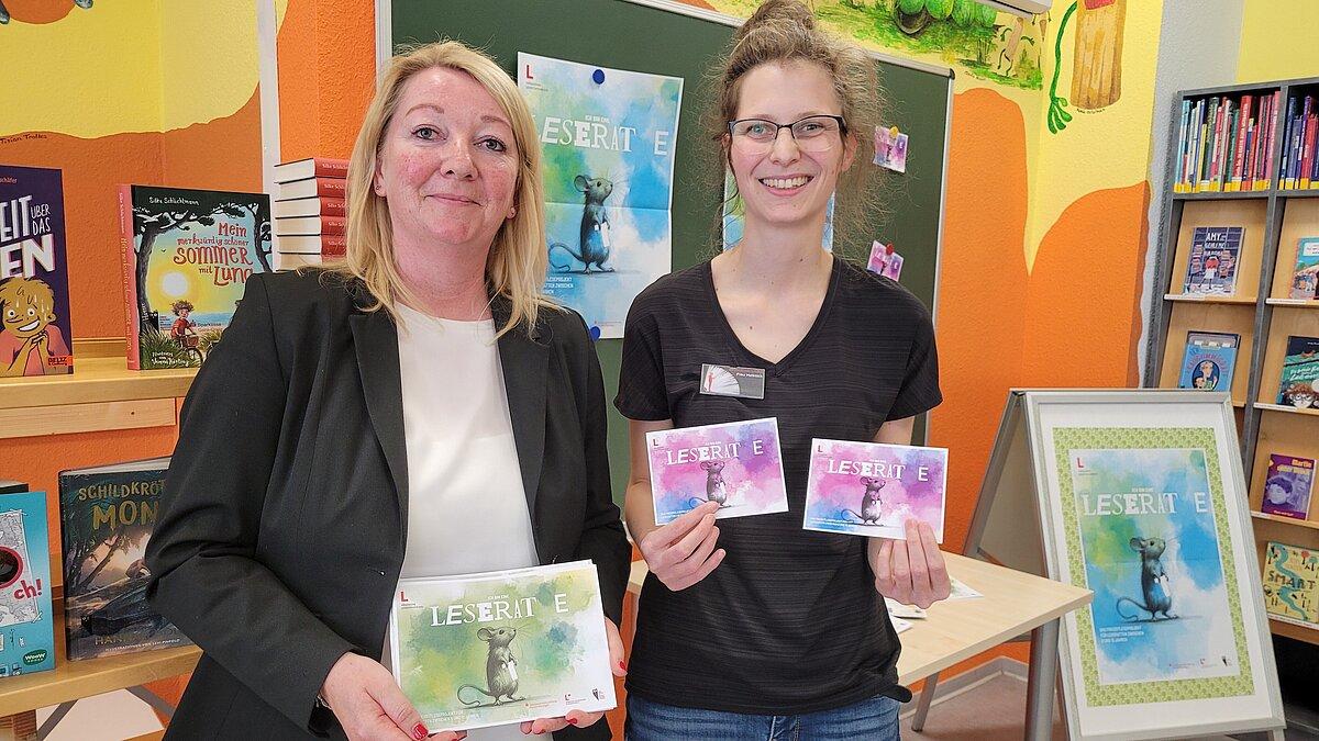Zwei Frauen zeigen Flyer von einer Veranstaltung. © Bibliothek / S. Hammer