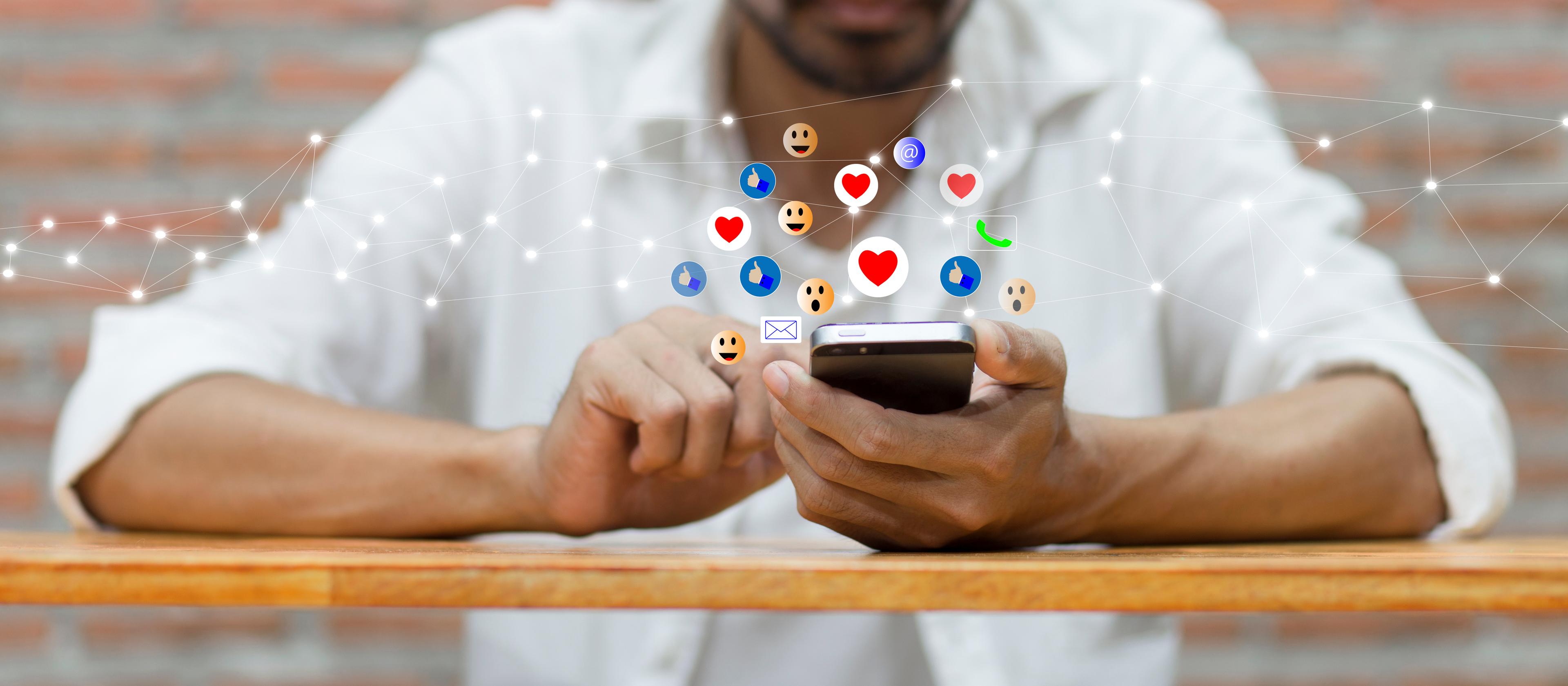Ein Mann hält ein Handy, um das Emojis schweben. © Surasak Chuaymoo - stock.adobe.com