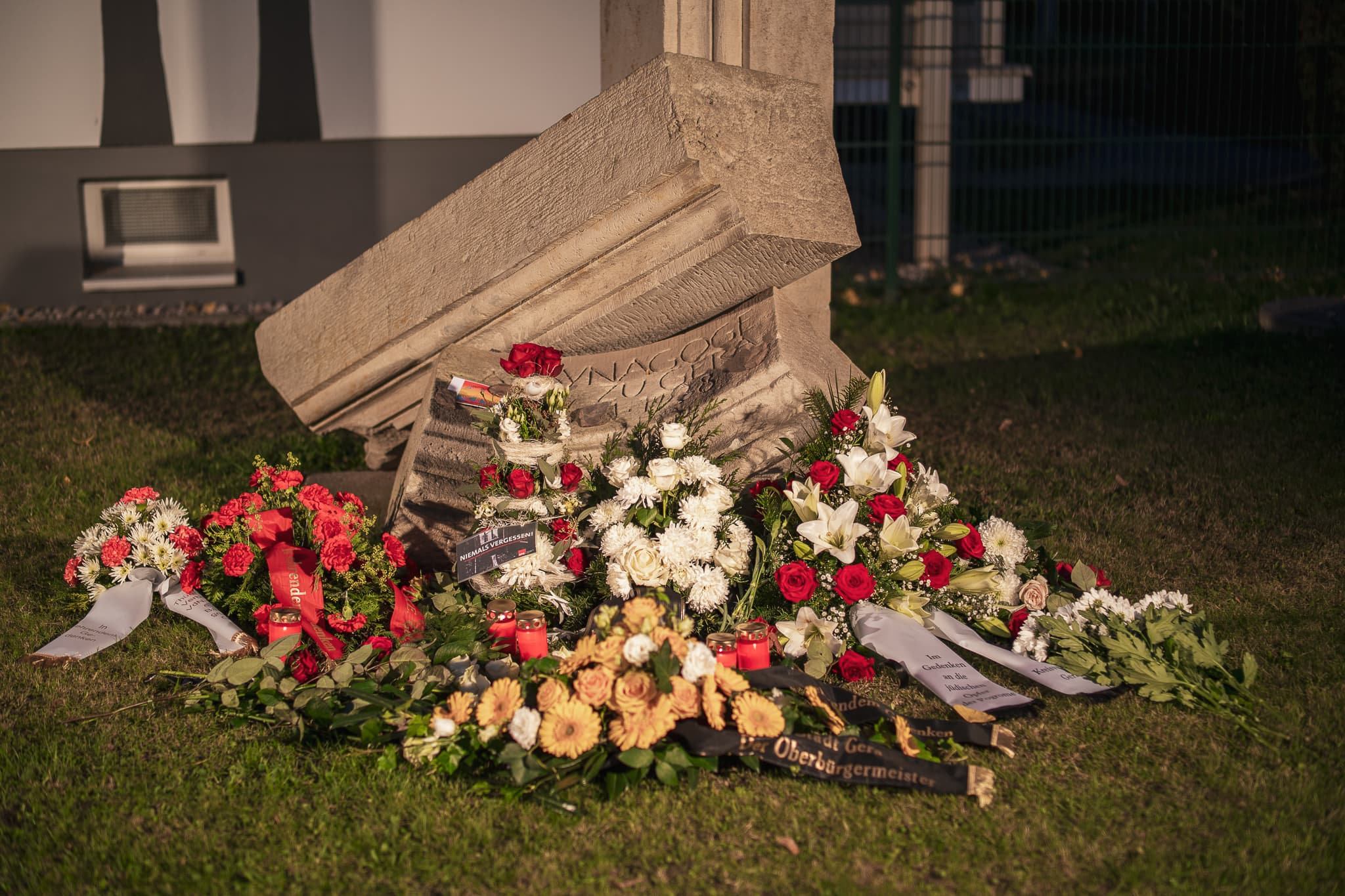 Gedenkstein, davor Blumenkränze