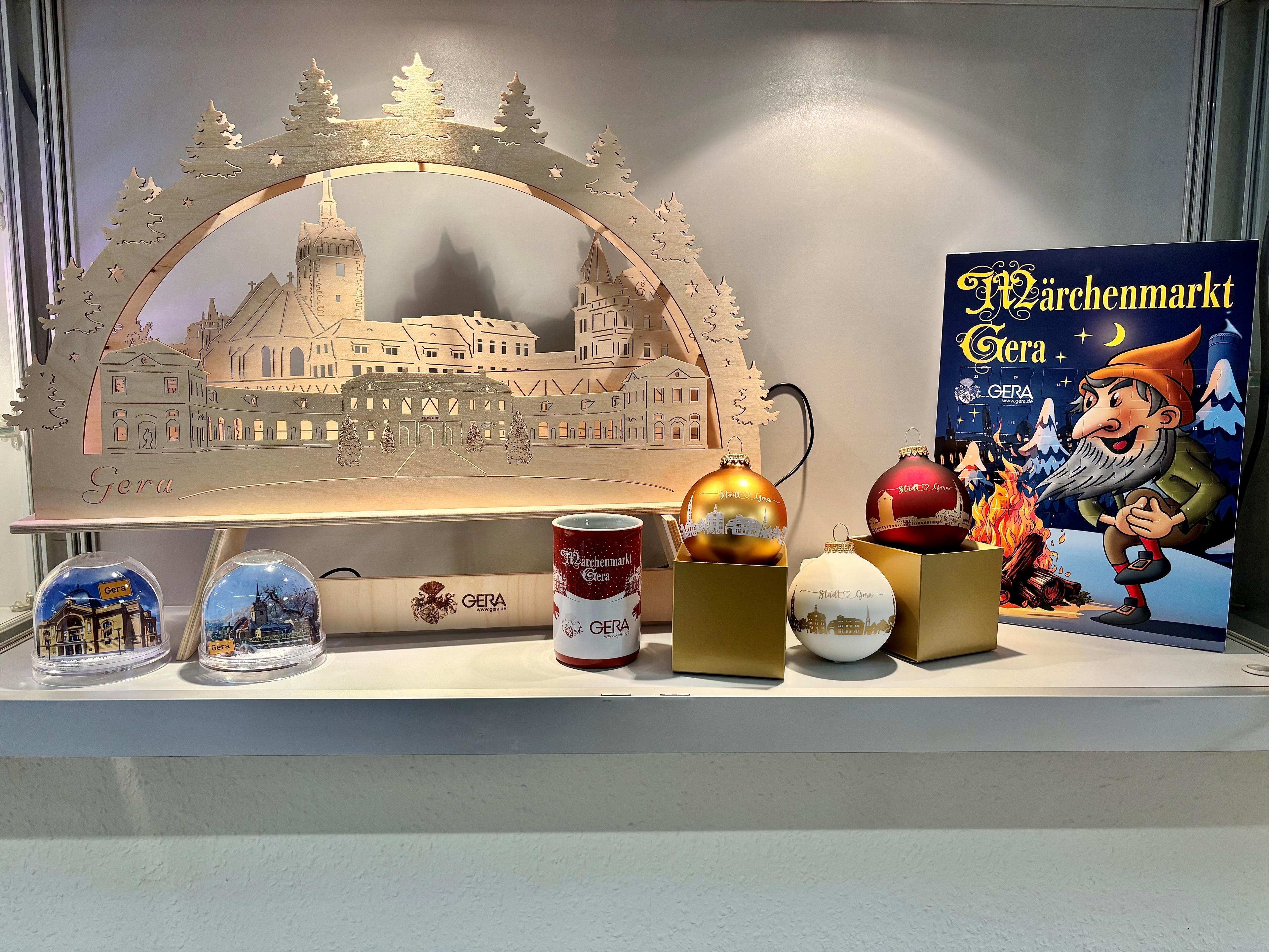 Ein Schwibbbogen, mehrere Weihnachtsbaumkugeln und ein Adventskalender auf einem Regal. © Stadt Gera