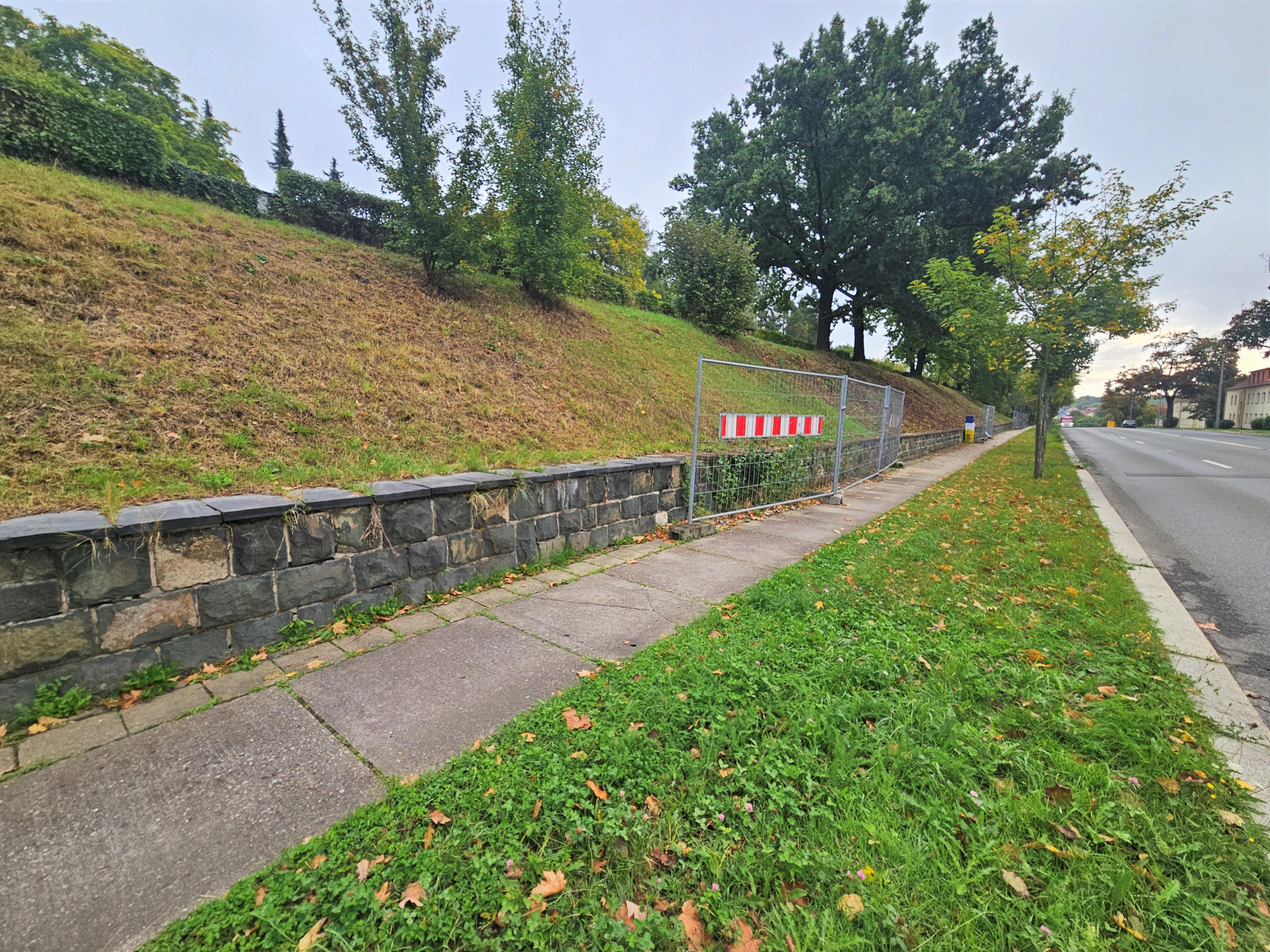 Eine lange Stützmauer an einem kleinen Hang, davor ein Gehweg. © Stadt Gera