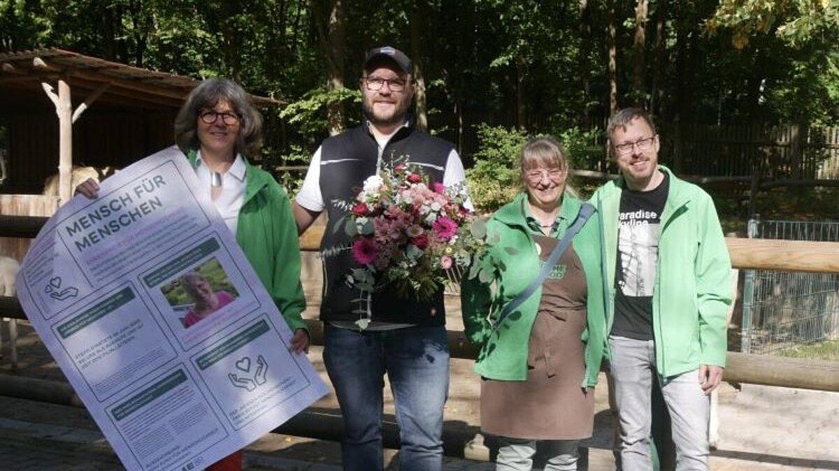 vier Menschen und eine Ziege stehen vor dem Tiergehege und präsentieren den Spendenscheck. © Blume2000
