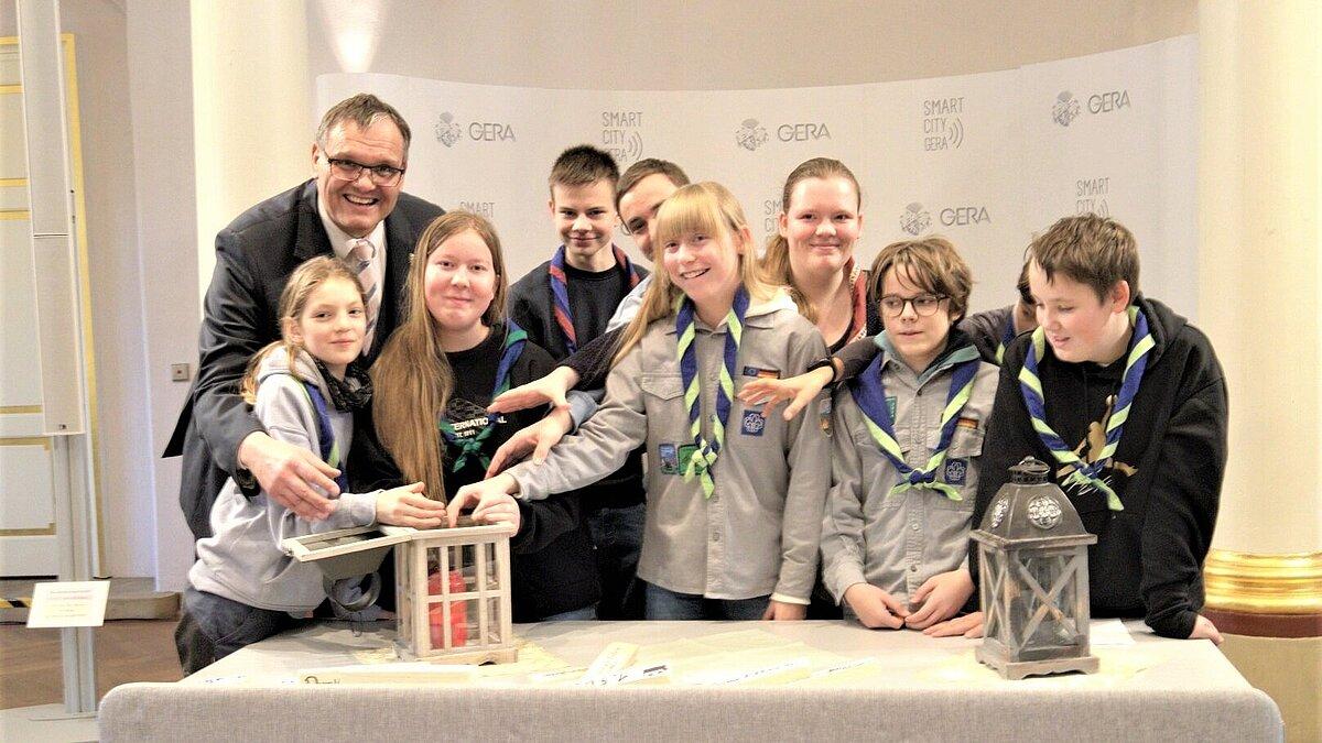 Mehrere Menschen vor einer Laterne, in der das Friedenslicht brennt. © Stadt Gera