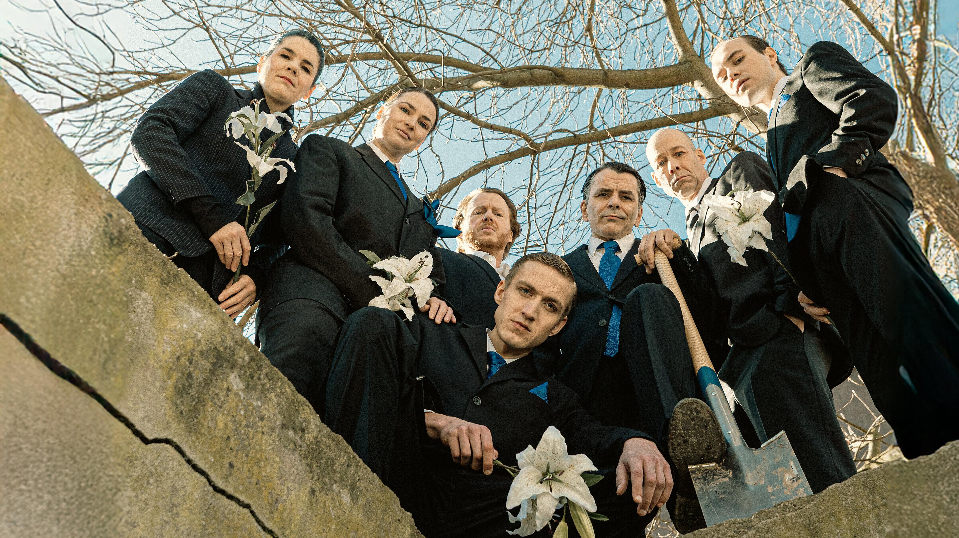 Eine Gruppe von Schauspielern gekleidet in Anzügen schaut von oben herab. © Theater Gera Altenburg