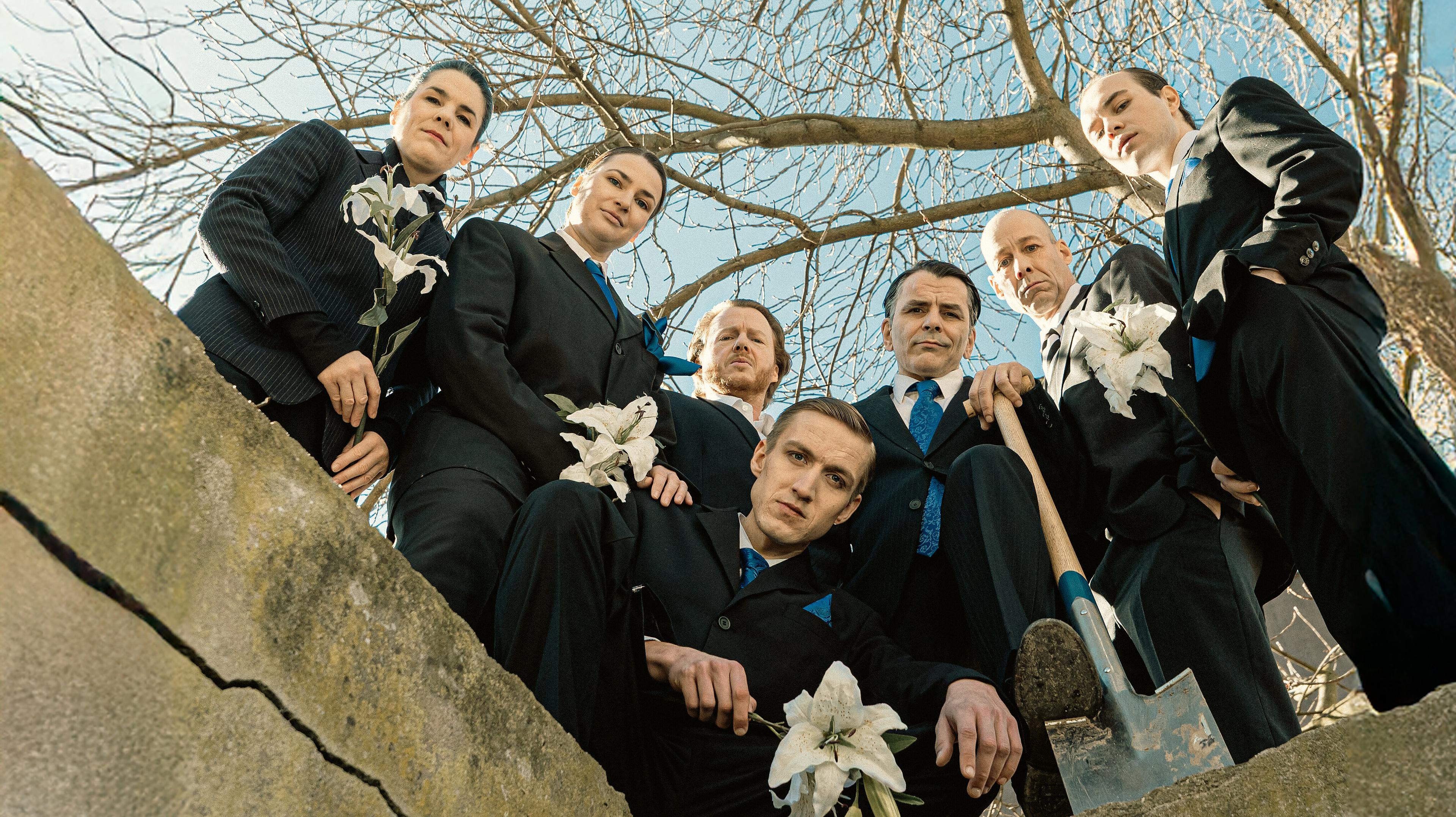 Eine Gruppe von Schauspielern gekleidet in Anzügen schaut von oben herab. © Theater Gera Altenburg