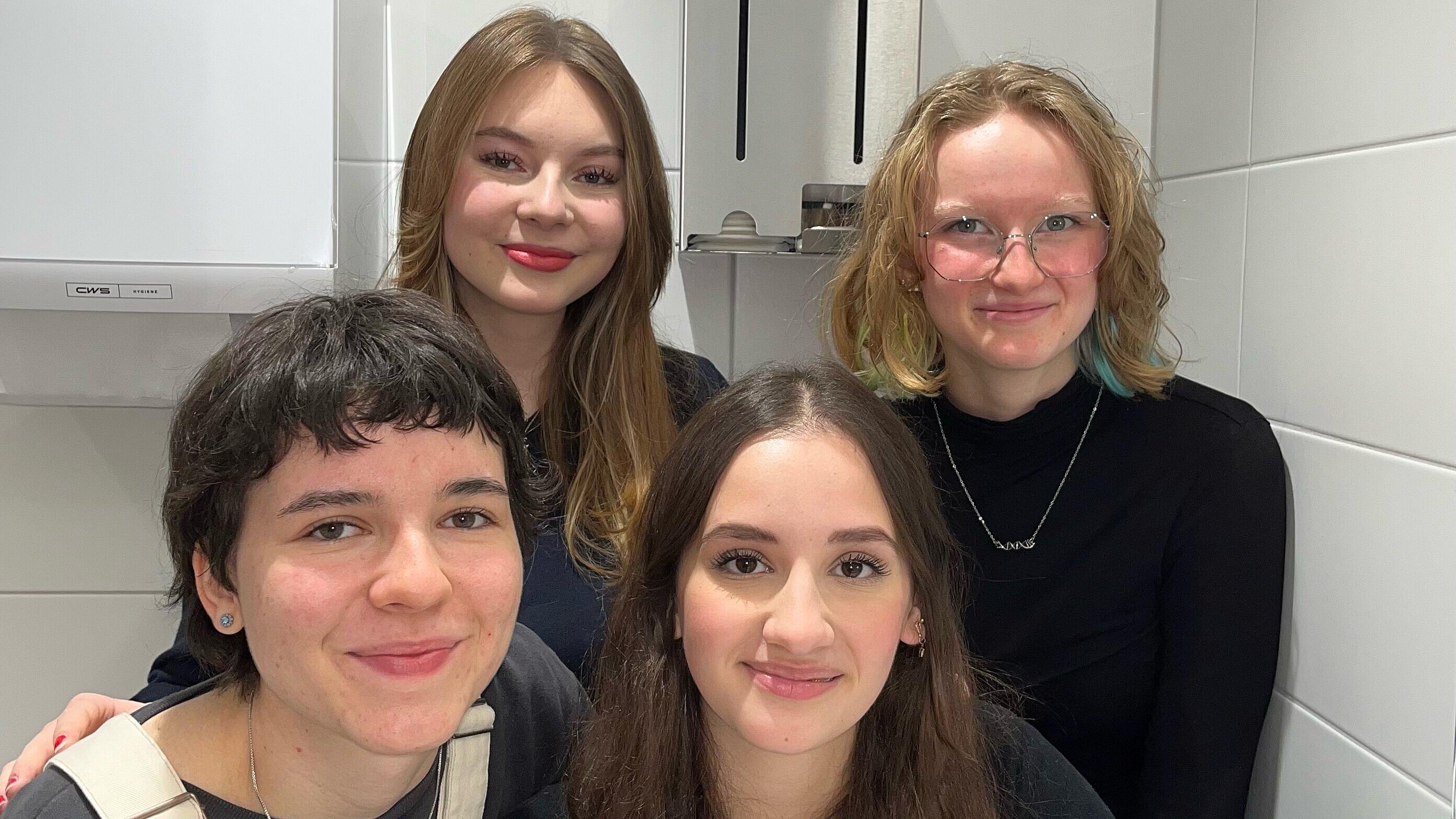An einem der grauen Spender für Binden und Tampons stehen hier die vier Schülerinnen Ella Wiesner und Lara-Maria Veltkamp mit der stellv. Schulsprecherin Dana Kablou und der Schulsprecherin Joanne Heinze.. © Josefina Paredes