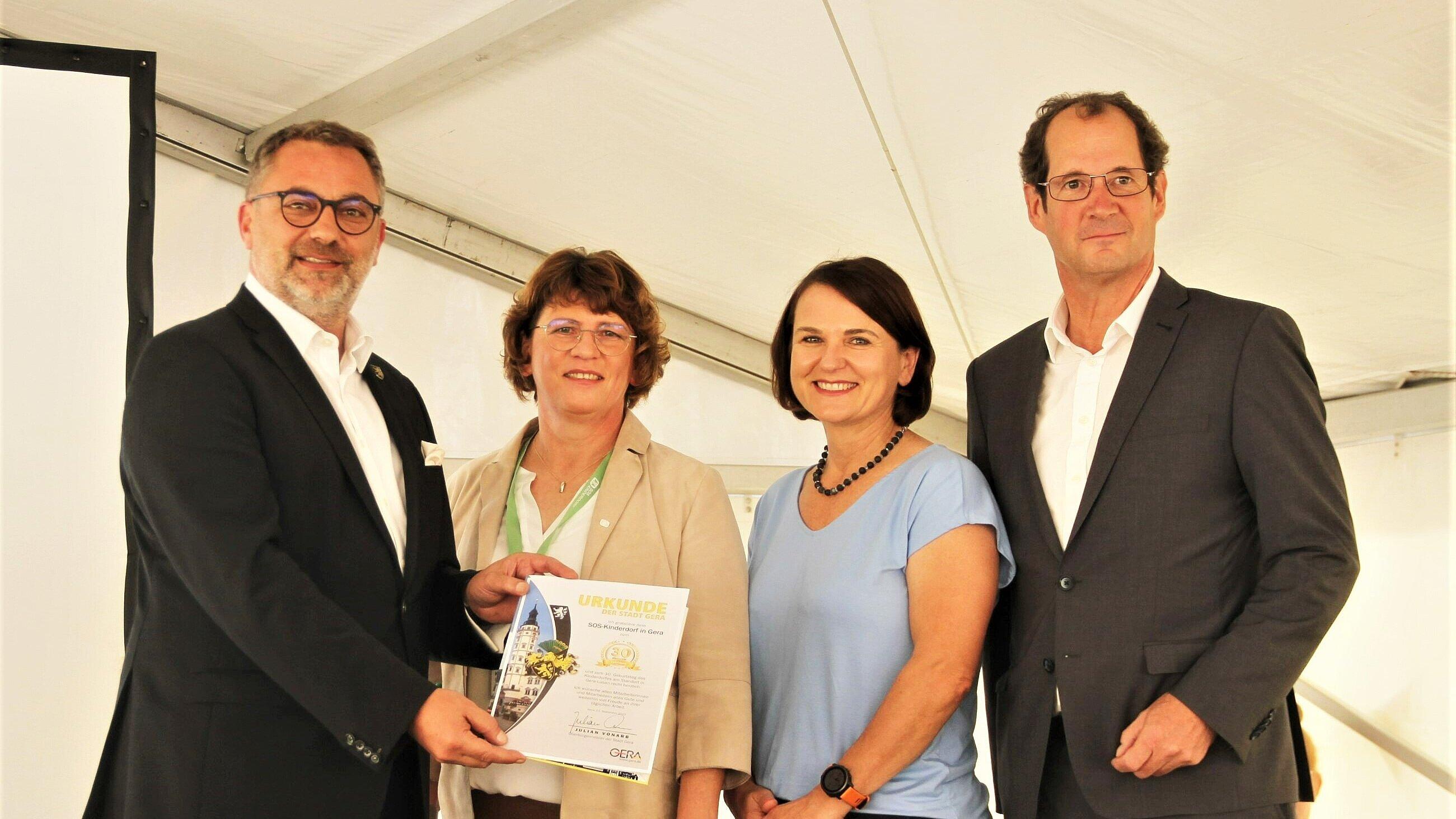 Oberbürgermeister Julian Vonarb überreicht die Jubiläumurkunde an Katrin Berthold (Einrichtungsleiterin SOS Kinderdorf), Maria Schwarzfischer (Regionalleitung SOS-Kinderdorf e.V.) sowie Georg Falterbaum (Vorstandsmitglied des SOS-Kinderdorf). © Stadt Gera