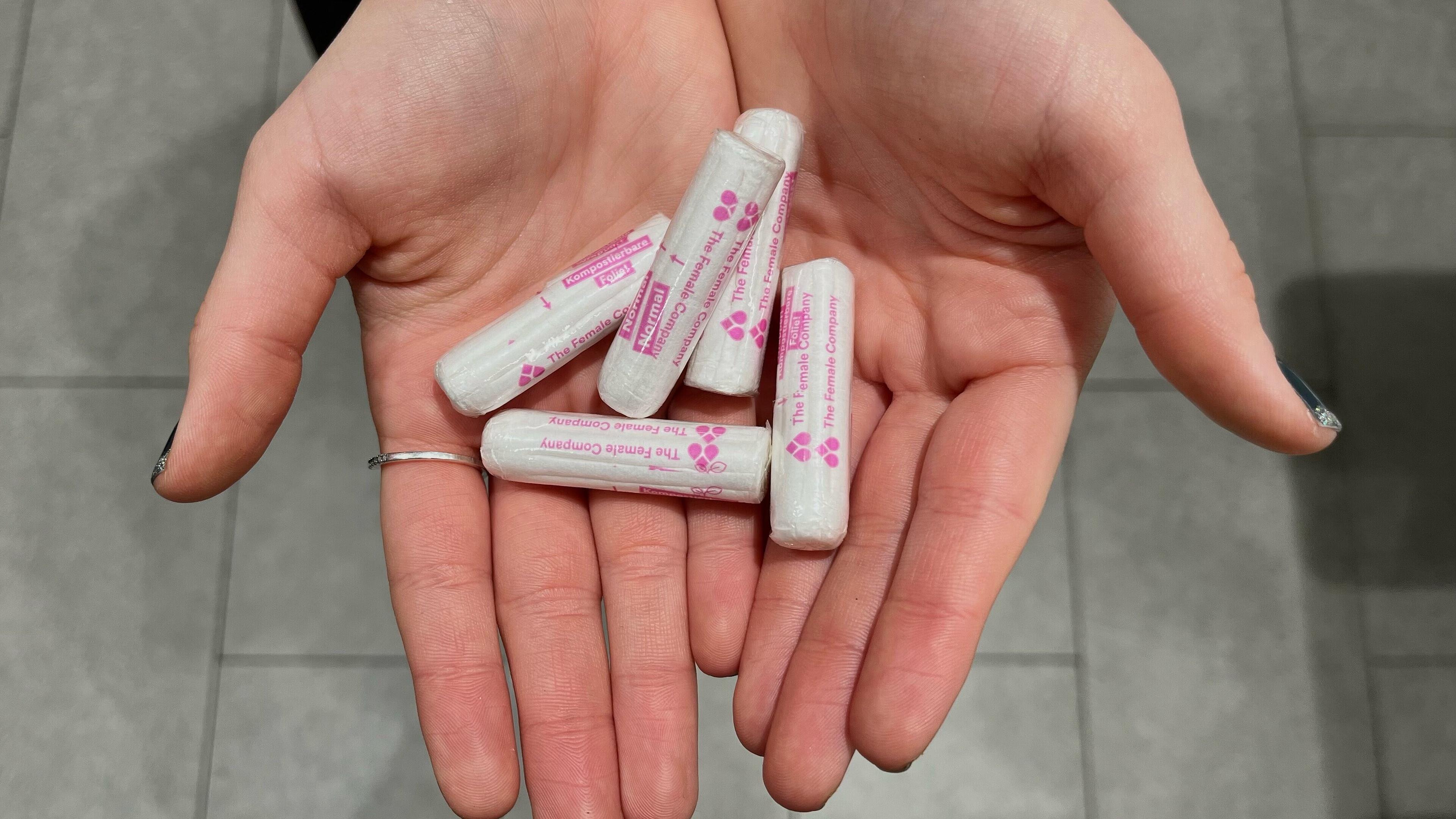 Eine Schülerin zeigt in ihren nach oben geöffneten Händen einige der Tampons, die beim Schultest kostenfrei im WC zur Verfügung stehen für alle. . © Lara-Maria Veltkamp