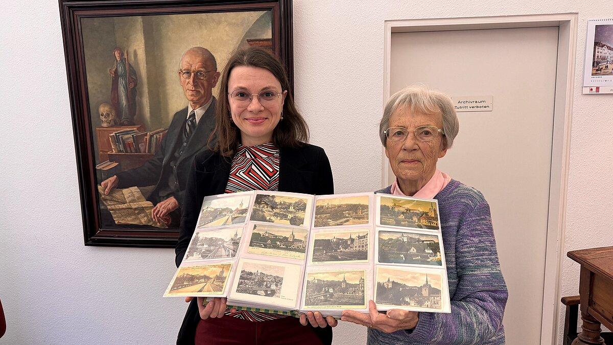 Archivleiterin Christel Gäbler (links) bei der Übernahme der Postkartensammlung zu Schloss Osterstein von Renate Stachorski (rechts) im Lesesaal des Stadtarchivs Gera. © Stadt Gera