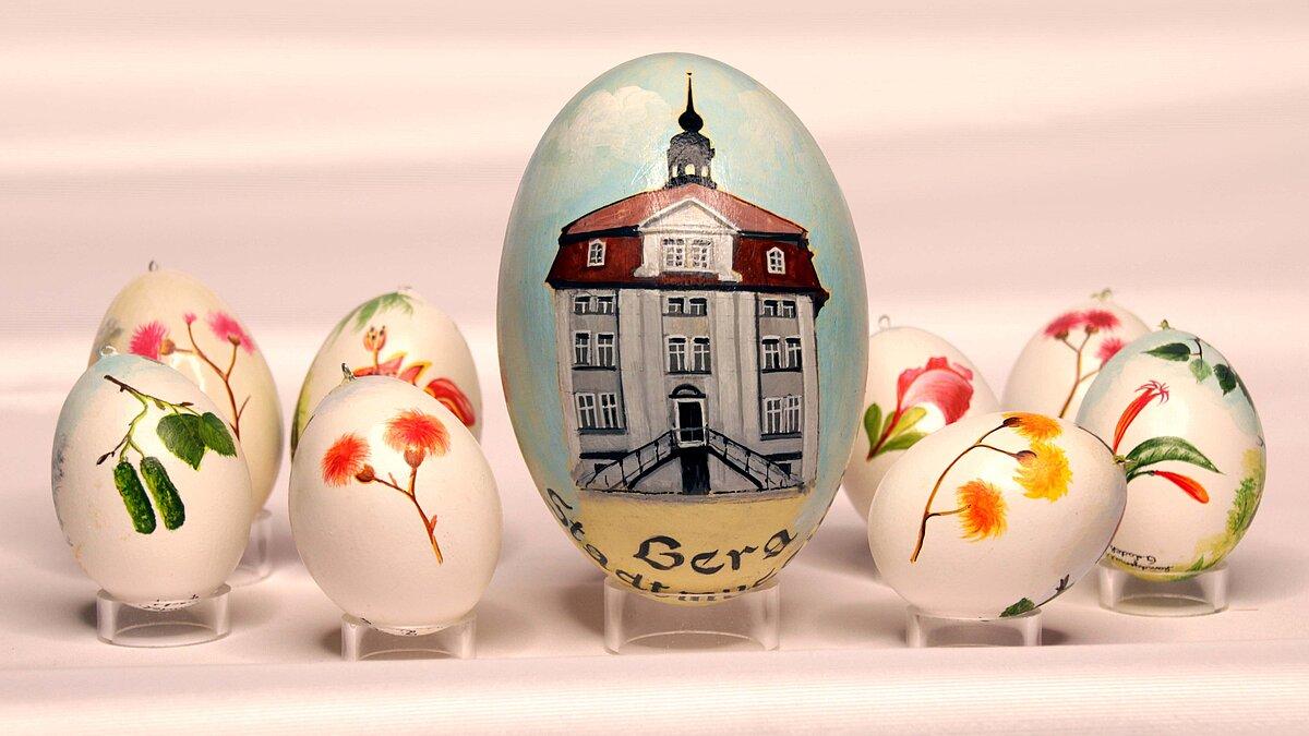 Das Osterei zeigt das markante Gebäude des Stadtmuseums, mit seiner Freitreppe und dem kleinen Türmchen auf dem Dach. Daneben sind Ostereier mit verschiedenen Pflanzenmotiven zu sehen. . © Günter Ladek