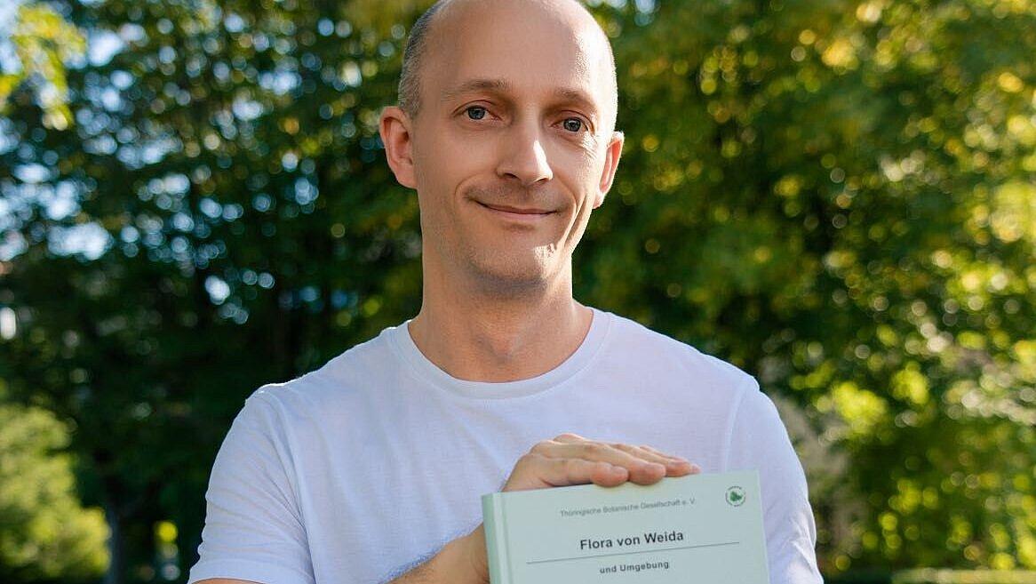 Autor Rico Kaufmann mit seinem Buch "Flora von Weida und Umgebung". © Man Yi
