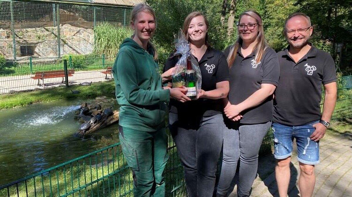 eine Tierpflegerin und drei Mitglieder des Fanfarenzugs Gera e.V. stehen zur Spendenübergabe am Teich der Wasserschildkröten im Tierpark Gera. © Stadtverwaltung Gera