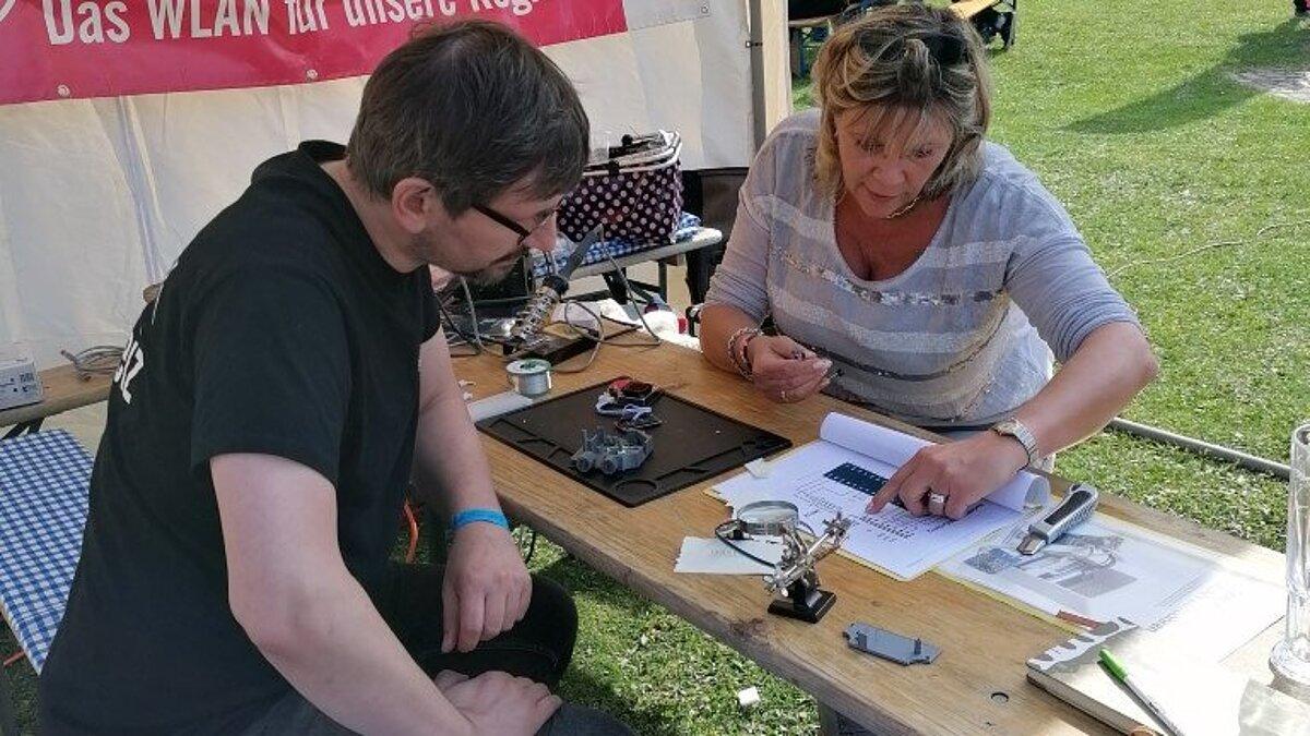 Eine Frau, die einem Mann die Vorteile des Freifunks auf einem Blatt Papier präsentiert