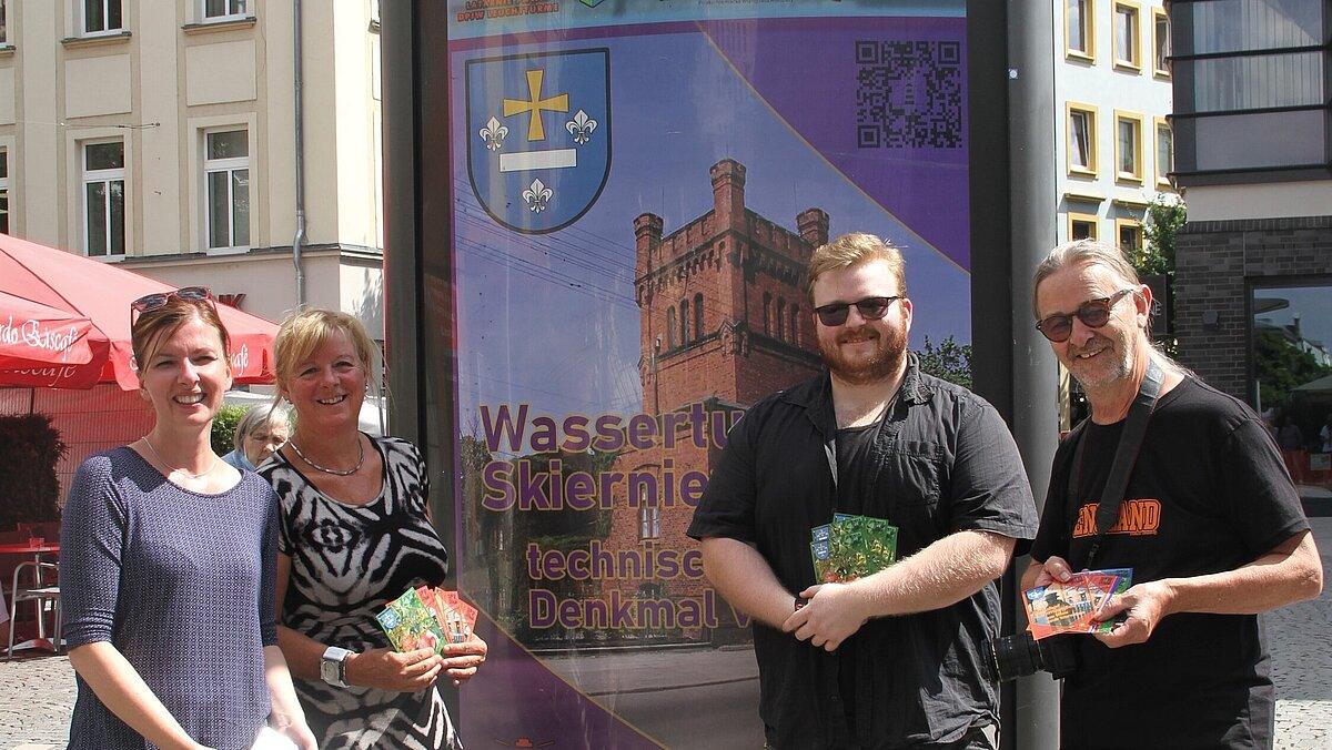 Christina Martens (Koordinatorin der Städtepartnerschaften) und Heike Födisch (Koordinatorin des Leuchtturmprojekts) gemeinsam mit dem Gestalter Christian Rösing und Fotografen Frank Rüdiger (v.l.n.r.) vor den Plakaten in der Schlossstraße.