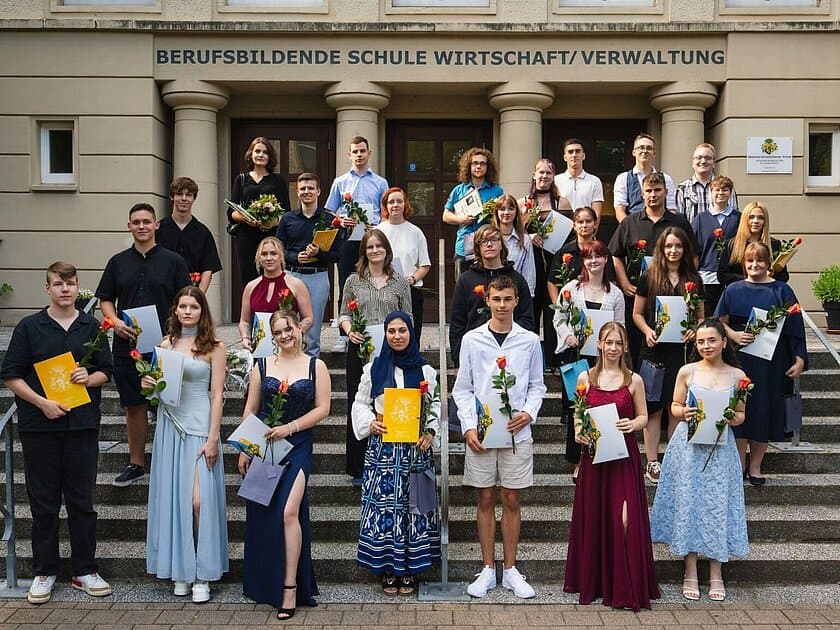 Gruppenbild der Absolventen auf einer Treppe mit Urkunden und Blumen in der Hand. © Echtbild / Hung Dinh