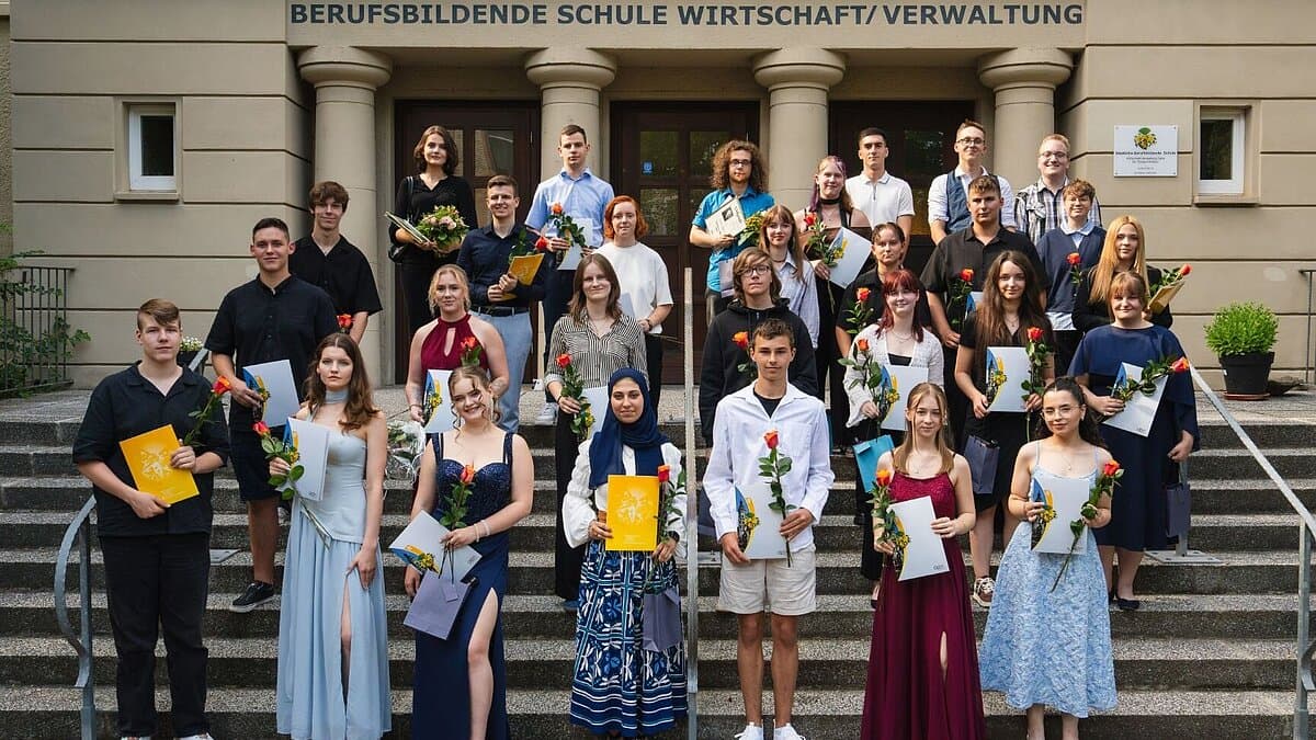 Gruppenbild der Absolventen auf einer Treppe mit Urkunden und Blumen in der Hand. © Echtbild / Hung Dinh