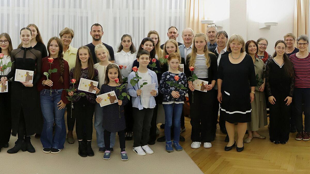 Die geförderten Kinder gemeinsam mit Erwachsenen in einer Gruppe im Konzertsaal, sie schauen in die Kamera. © Stadt Gera