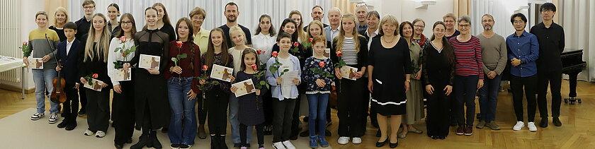 Die geförderten Kinder gemeinsam mit Erwachsenen in einer Gruppe im Konzertsaal, sie schauen in die Kamera. © Stadt Gera