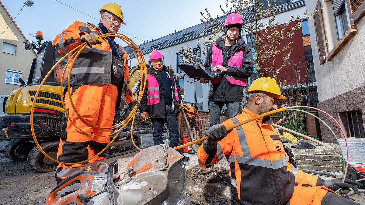 Mitarbeiter der Telekom führen ein Kabel von außen in ein Gebäude ein.. © Telekom