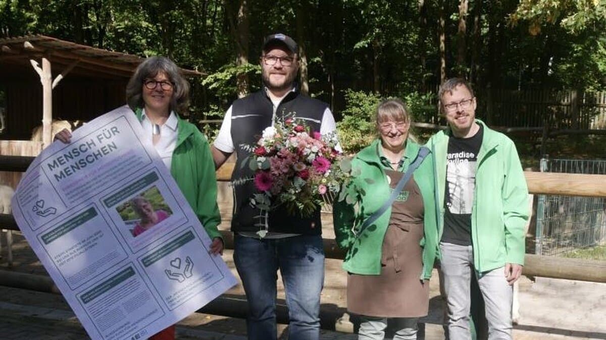 vier Menschen und eine Ziege stehen vor dem Tiergehege und präsentieren den Spendenscheck. © Blume2000